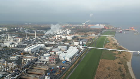 smoke and steam rising of an industrial facility on a river, co2 emissions, air pollution, exhaust gases, aerial