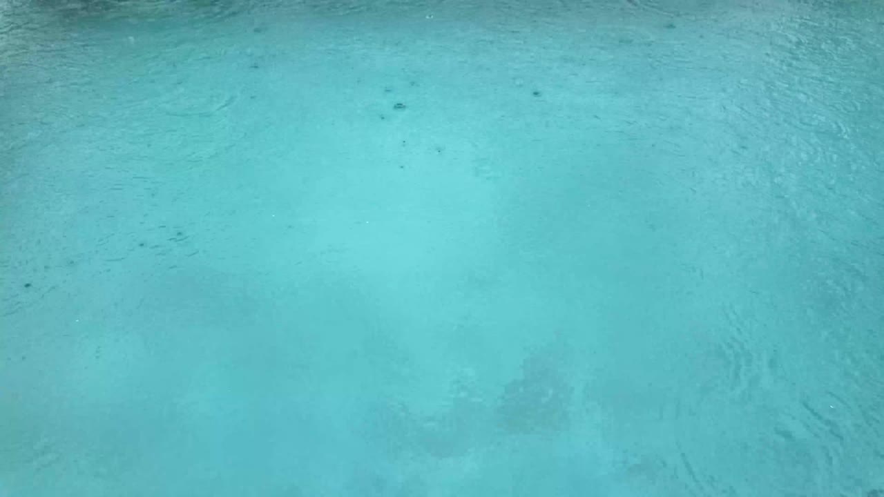 Rain heavy downpour over water surface swimming pool light blue color bad weather