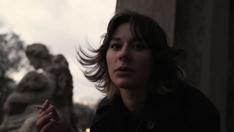 young woman in a black coat standing on a terrace enjoying the view and smoke-1