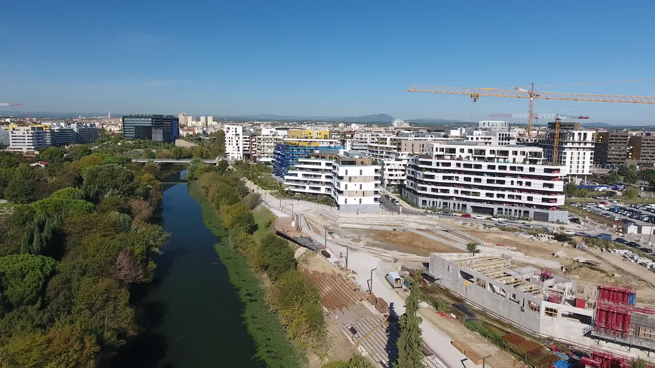 volando a lo largo de un río y un sitio de construcción con una grúa torre. vista aérea de drones