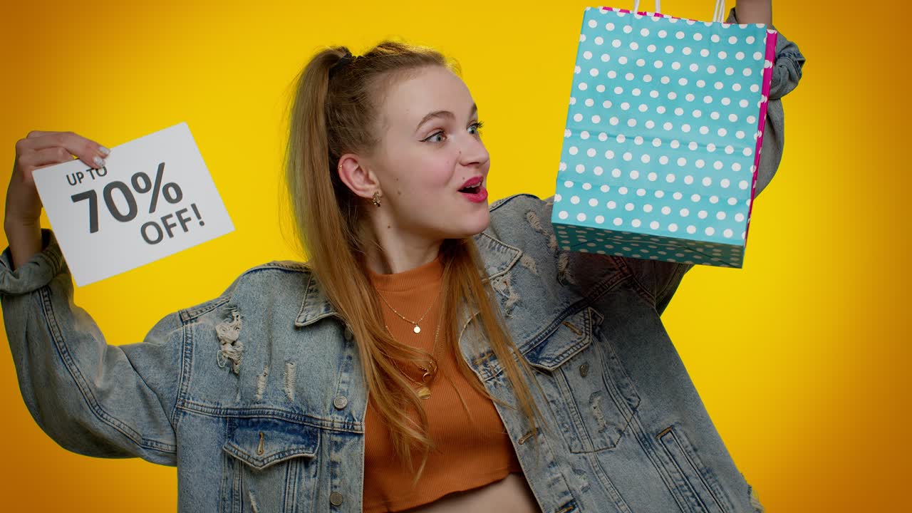 una adolescente alegre mostrando bolsas de compras y hasta un 70 por ciento de descuento en las inscripciones del cartel, black friday