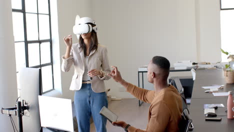 using vr headset, woman interacting with colleague holding tablet in office