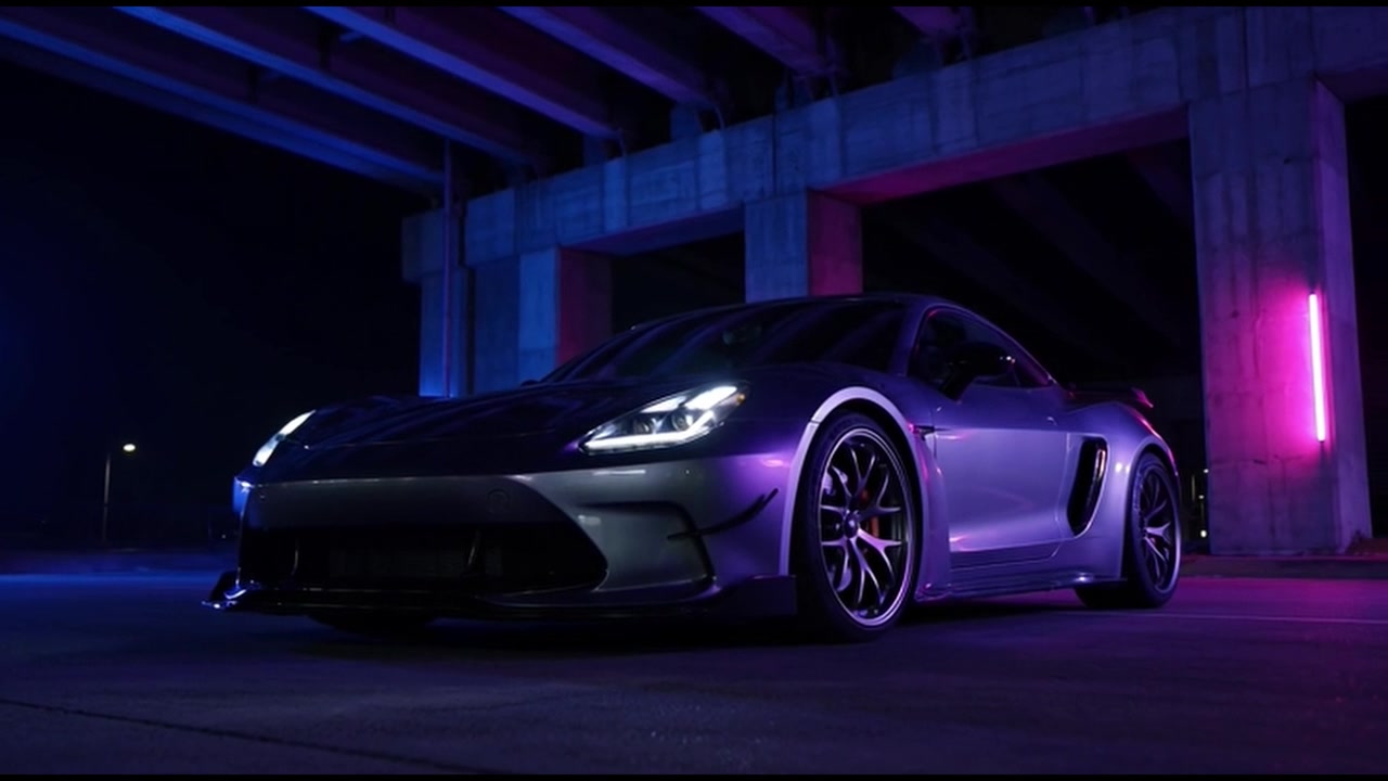 Auto sportiva argentata parcheggiata sotto un ponte di cemento di notte