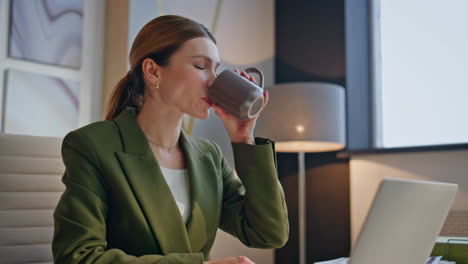relaxed businesswoman enjoy coffee break sitting modern office desk closeup