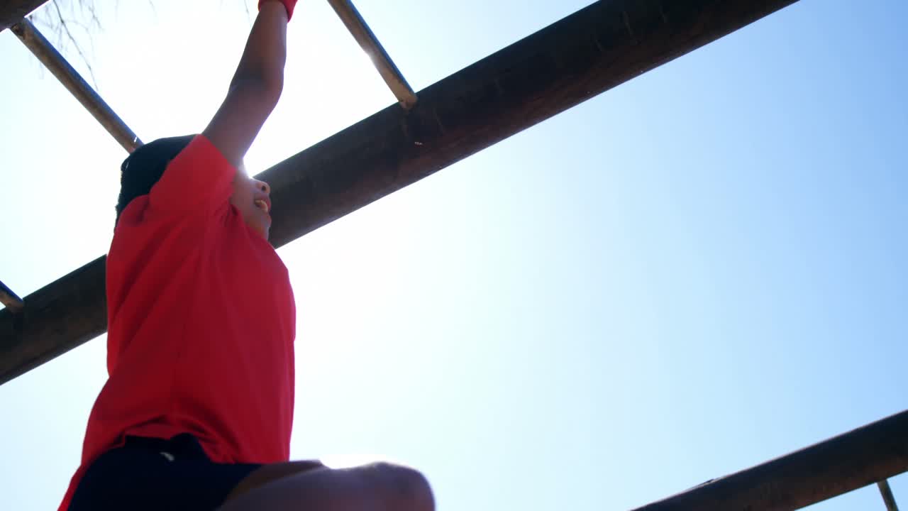 chica escalando en una barra de monos en el campamento de entrenamiento