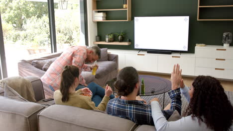 excited diverse male and female friends watching sport on tv at home, copy space on screen