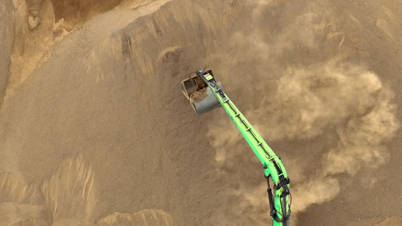 큰 모래 더미 를 파고 모래 를 들어 올리고 먼지 구름 을 만들어내는 발굴기 의 공중 촬영