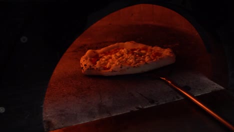 pizza baking in an italian pizza oven with fire around it in slow motion