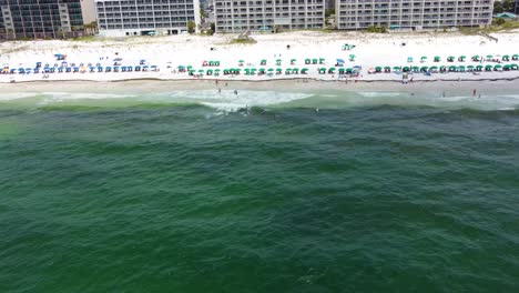Aerial view of turquoise green water of gulf of Mexico Infront of Building resorts on fort Walton beach Destin Florida. Tourist chairs umbrellas lined up on white sandy beach