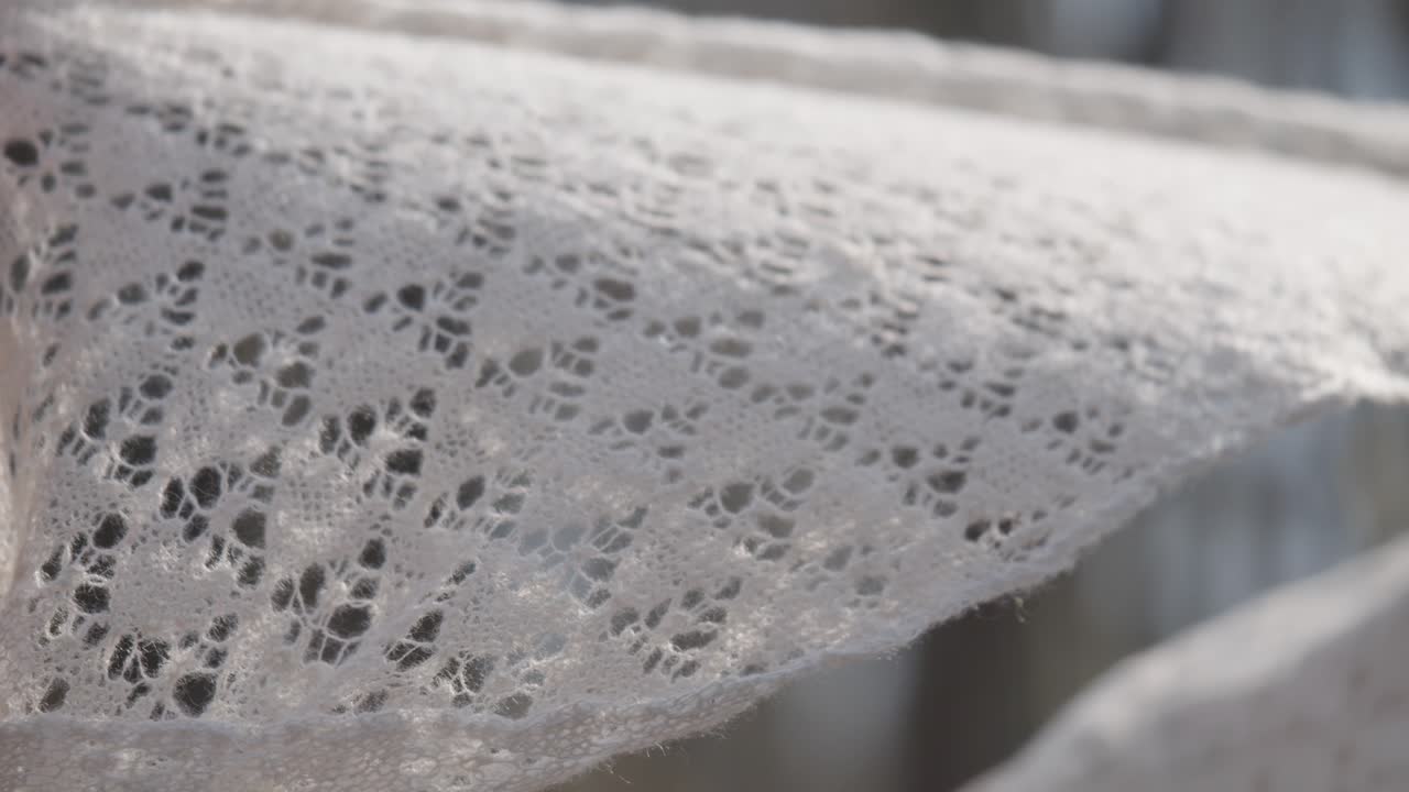Hands holding a white cashmere shawl as a delicate scarf in bright natural light.