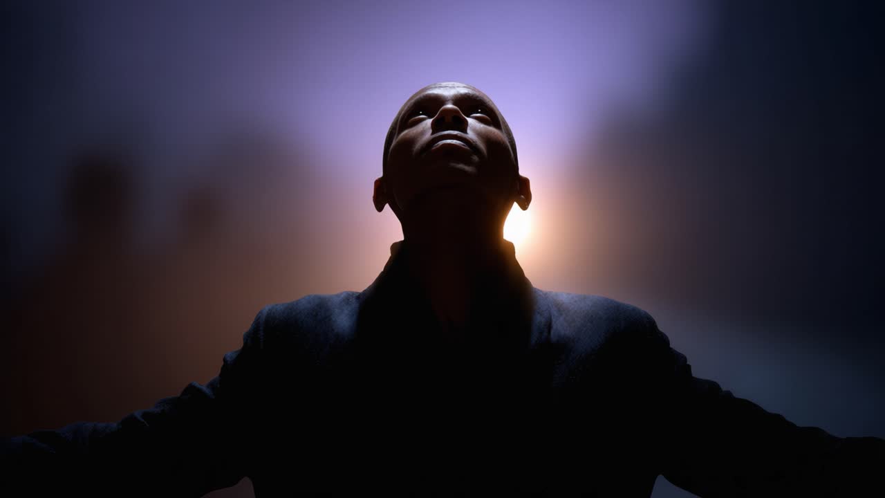 Una silhouette di un uomo con le braccia tese, che celebra un momento di illuminazione su uno sfondo di luce soffusa e un'atmosfera nebbiosa