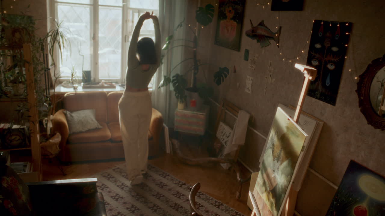 Ragazza rilassata con le cuffie che balla in uno studio d'arte domestico