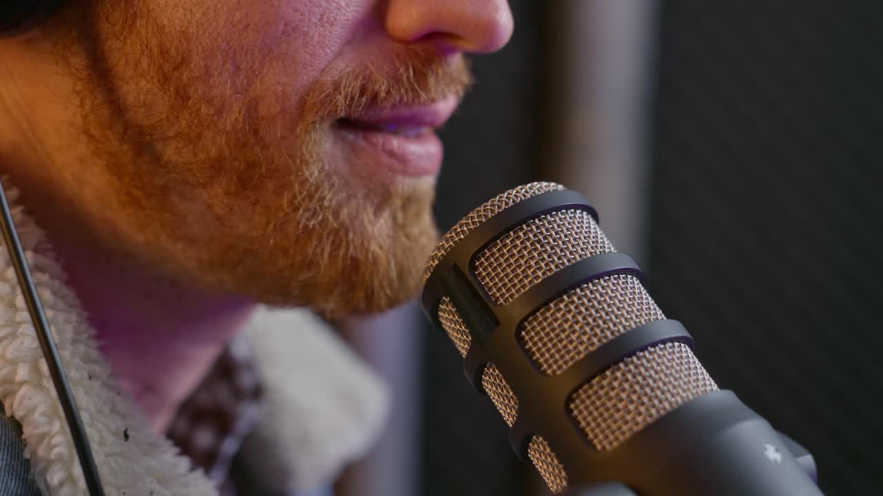 cerca de la boca de la persona hablando con el micrófono en un estudio de sonido o cabina de grabación. equipo de audio profesional. presentador de podcast o invitado de radio hablando. hombre con barba y auriculares en sesión en vivo