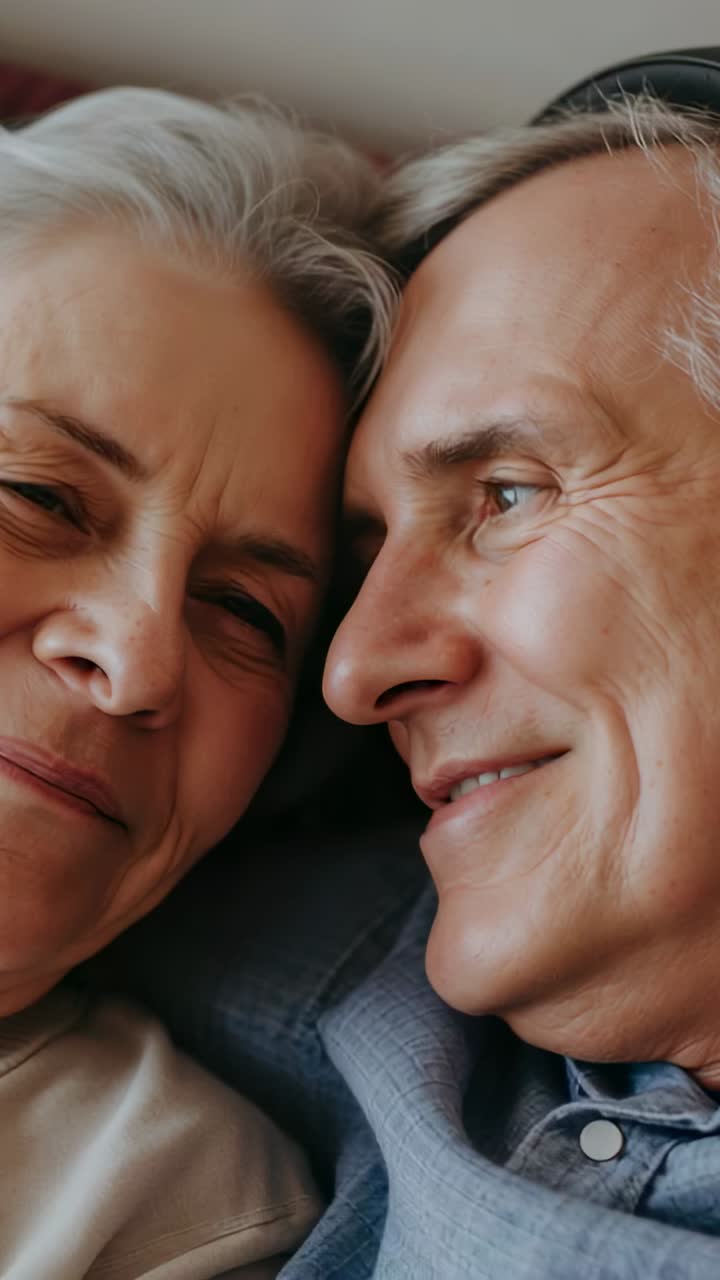 Vertical video: Shifting gaze man smiling at woman, reclining on sofa in blue shirt, showing love