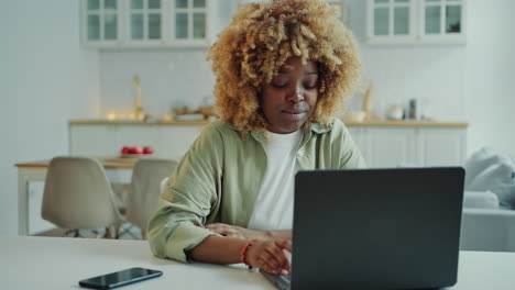 young black woman speaking via video call on laptop at home