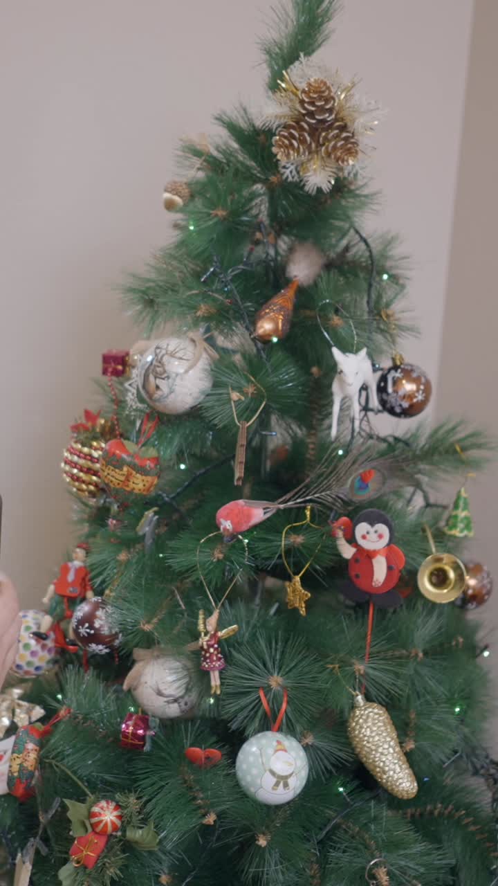 Hands holding a smartphone with a green screen in front of a decorated Christmas tree