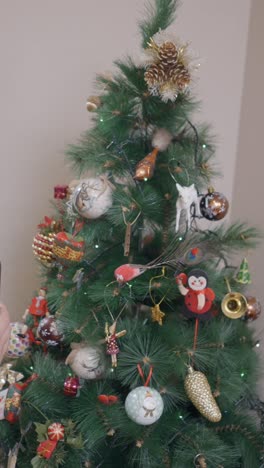 hands holding a smartphone with a green screen in front of a decorated christmas tree