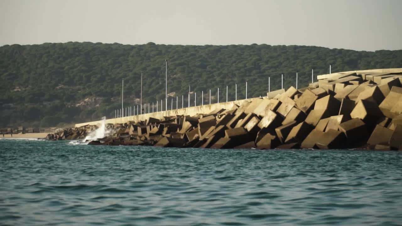 olas de agua de mar chocando contra un malecón de piedras cuadradas para evitar la erosión