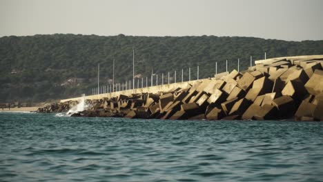 sea water waves crashing against a seawall of square stones to prevent erosion