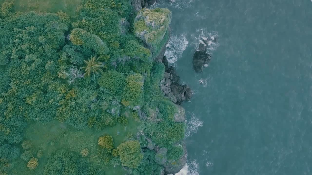 Cinematic aerial drone view of a picturesque landscape of ocean meeting mountains in Batanes, Philippines.