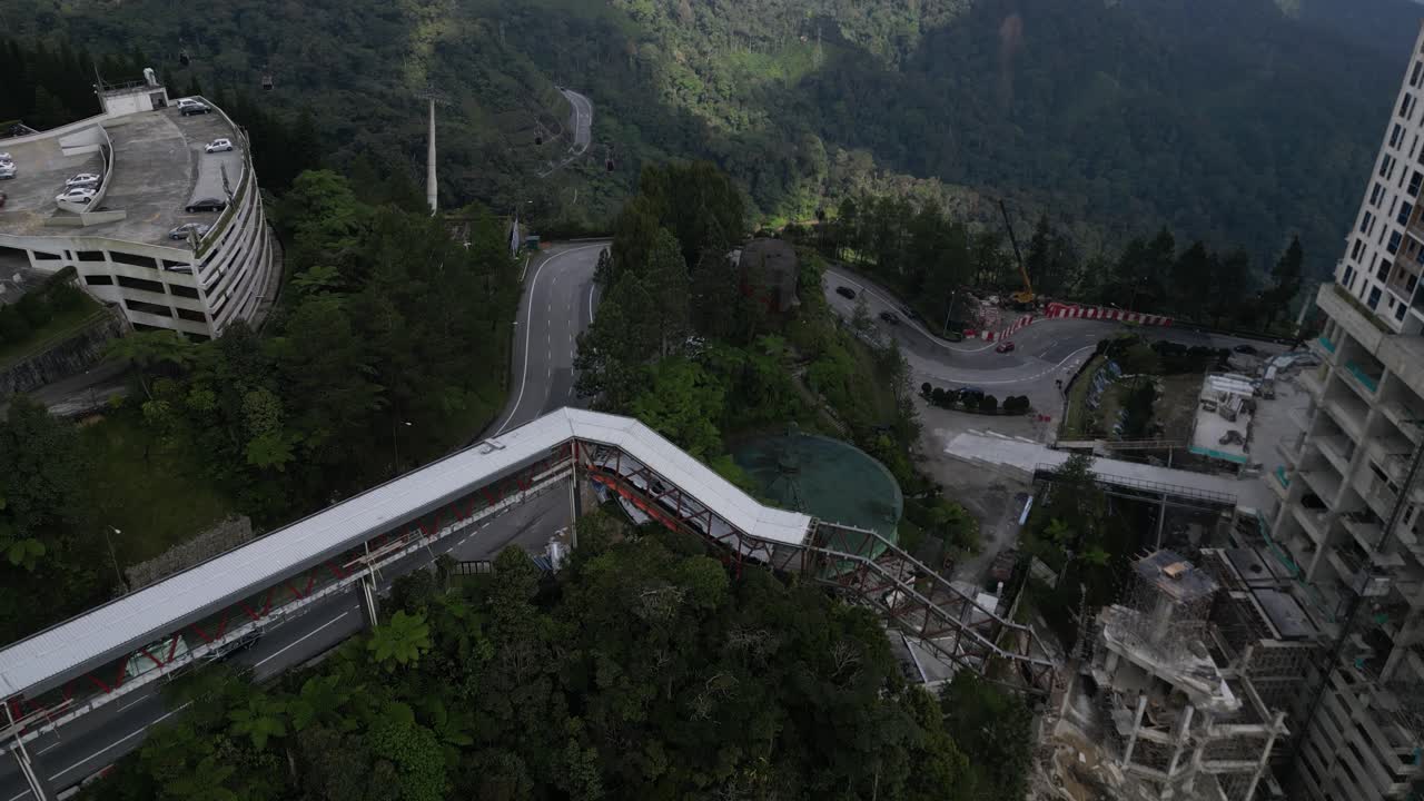 Drone flies over a road in the genting highlands in malaysia - background nature and many mountains with a cable car