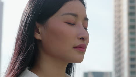 close-up profile of a young asian woman looking up and smiling in an urban setting