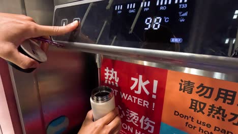 person adjusting water temperature on digital dispenser