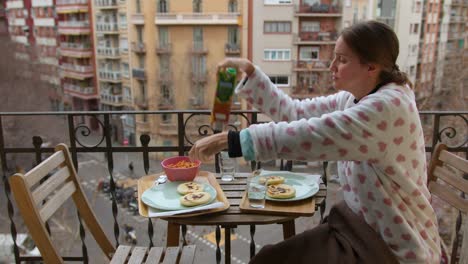 woman in pajamas sitting enjoying breakfast arepas on balcony during winter bliss city background