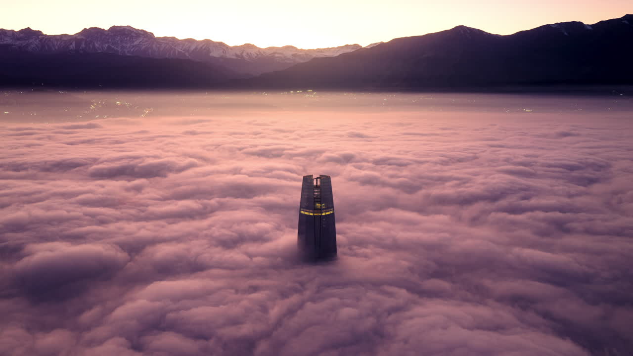 Aerial hyperlapse zoom in of the Costanera Center skyscraper surrounded by clouds during sunrise in Santiago