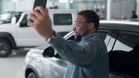 joyful black guy takes a selfie in a car dealership