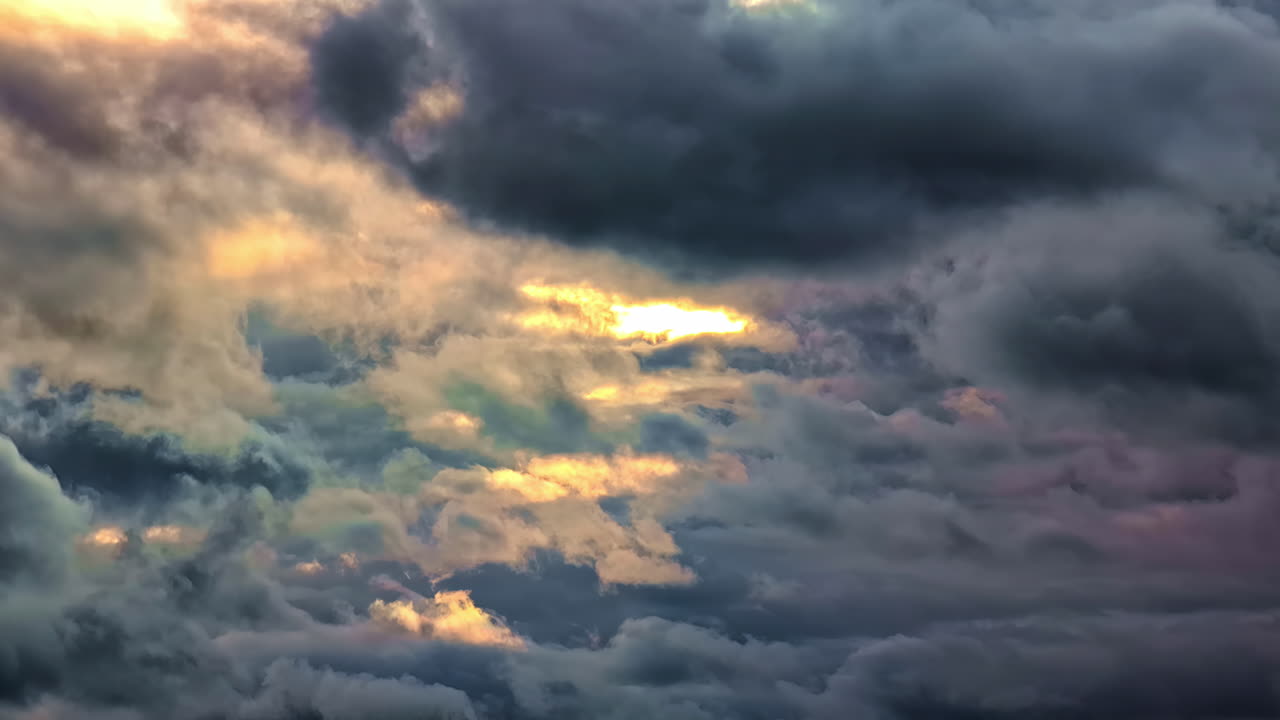 Dramatic sky with dark storm clouds with glowing colors and light breaking through
