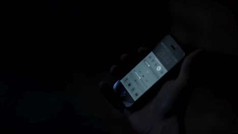 person adjusting volume on smartphone at night