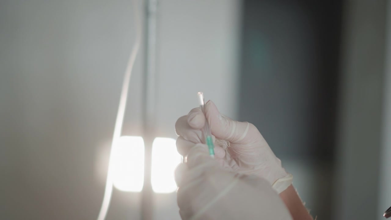 Enfermeira prepara medicação. Profissional de saúde administra tratamento intravenoso com precisão. Equipe médica retira meticulosamente medicação de frasco sob luz brilhante para tratamento do paciente.