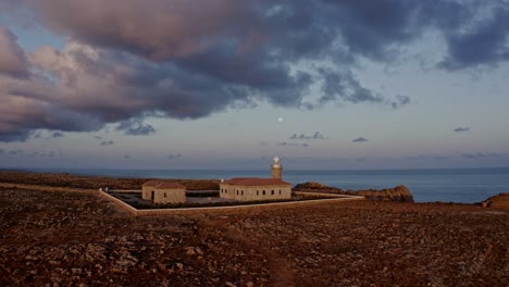 aerial reveal of punta nati lighthouse in menorca spain at sunset