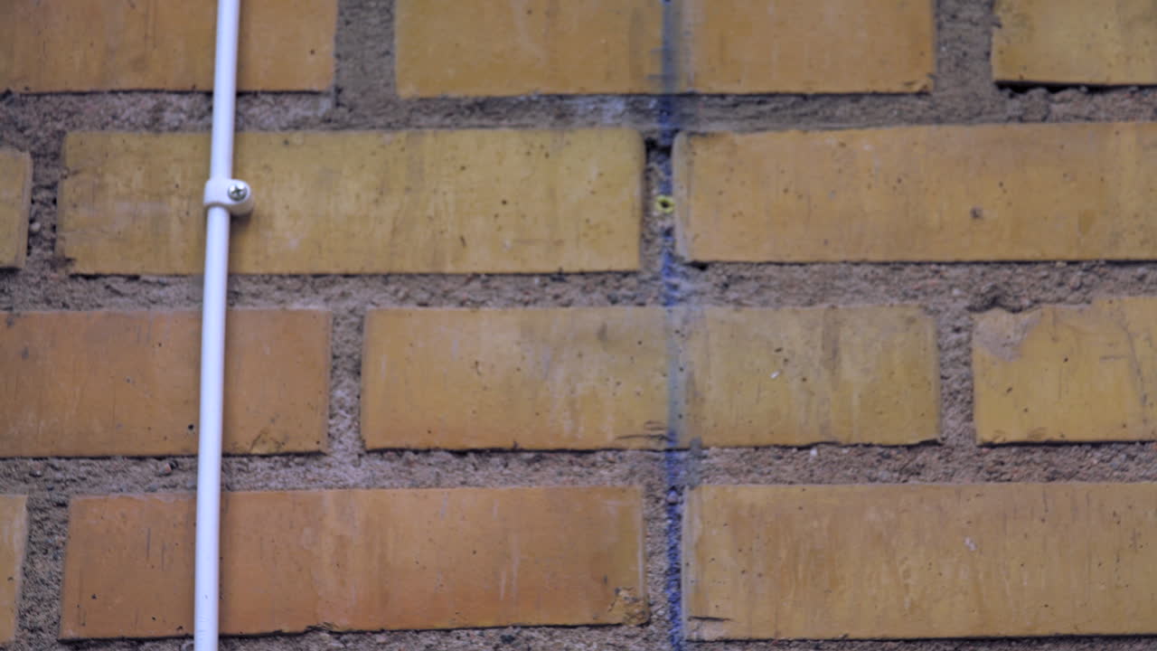 Tilt down shot to a closeup of a yellow and orange brick and mortar wall and a mounted white lightswitch that glows red