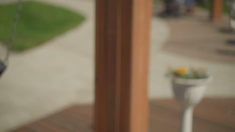 close-up of woman swinging outdoors, her hair moving with the breeze, with a blurred view of people in the background in a sunny park setting