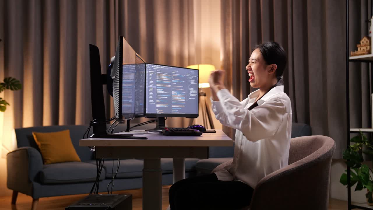 아시아 여성 프로그래머가 성공을 축하합니다. 소프트웨어 엔지니어가 집에서 데스크 컴퓨터에서 앱, 프로그램, 비디오 게임을 개발합니다. 코딩 언어를 가진 터미널.