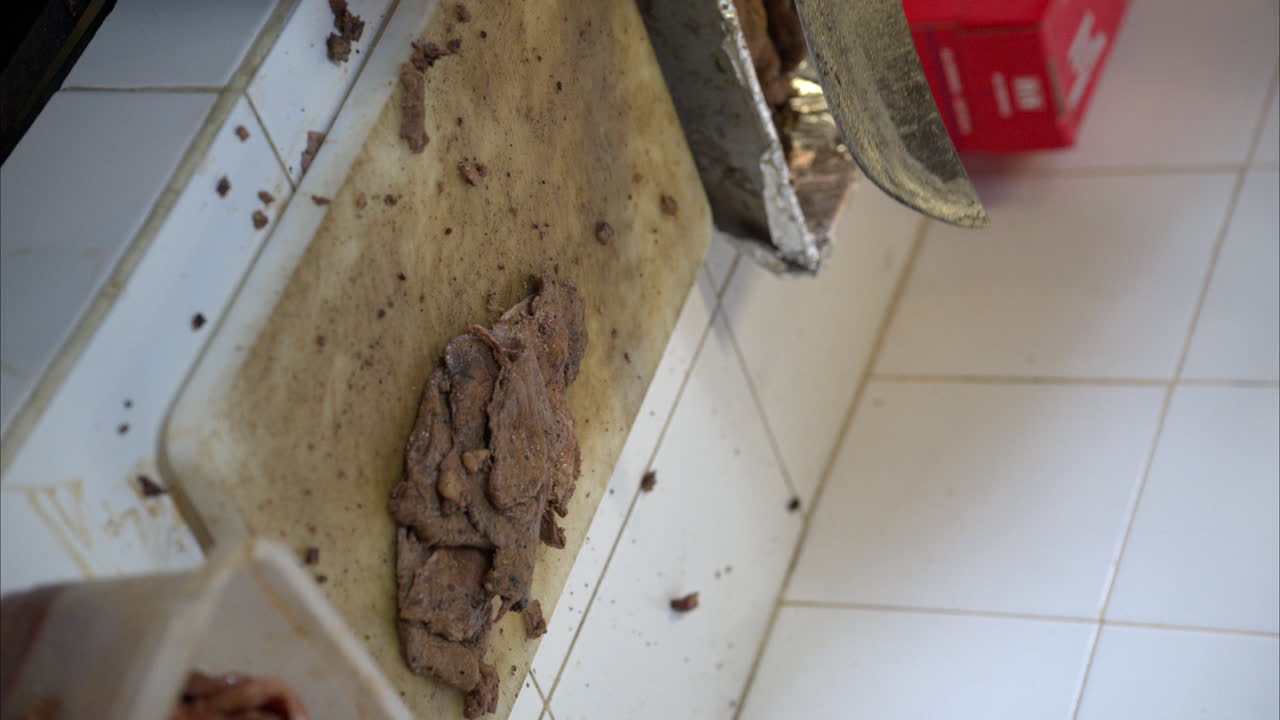 movimiento lento vertical cerca de un cocinero latino hispano con guantes de látex negro cortando carne picada con un cuchillo grande