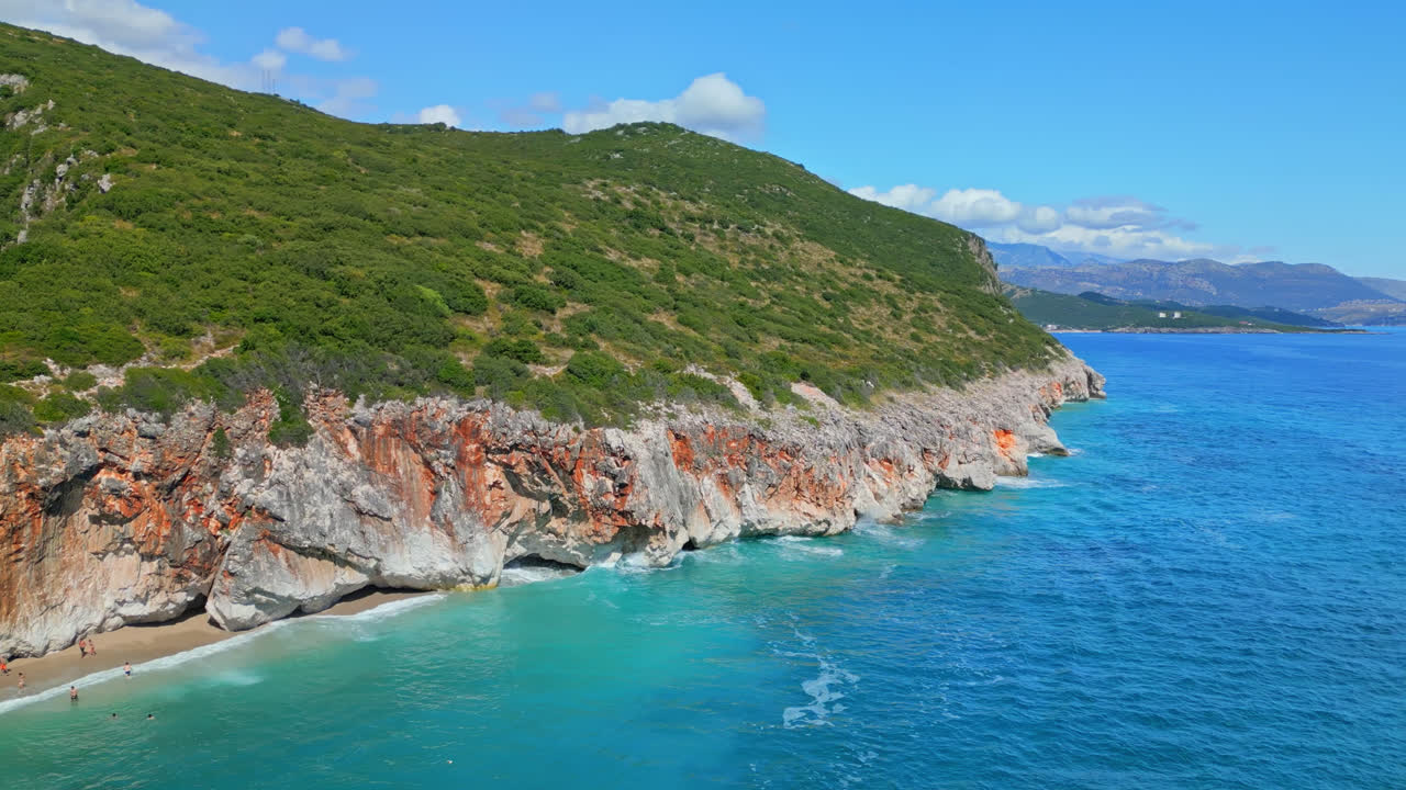 알바니아의 gijpe 해변을 가로질러 날씨가 좋은 날에 가파른 절벽을 따라 움직이는 공중 드론