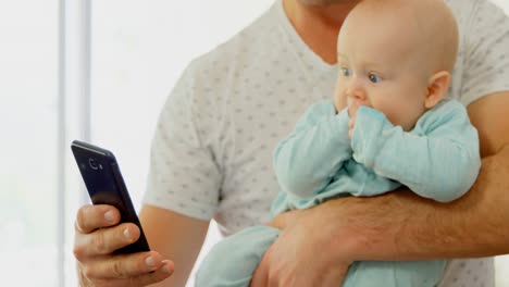 Vater-Und-Kleiner-Junge-Benutzen-Mobiltelefon-Im-Wohnzimmer-4k