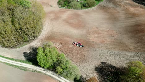 un tractor trabajando en un campo entre árboles en un bosque como se ve a través de los ojos de un avión no tripulado
