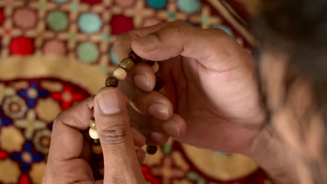 man's hand with wooden prayer beads, goes through prayer beads, blurred background. muslim prayer.