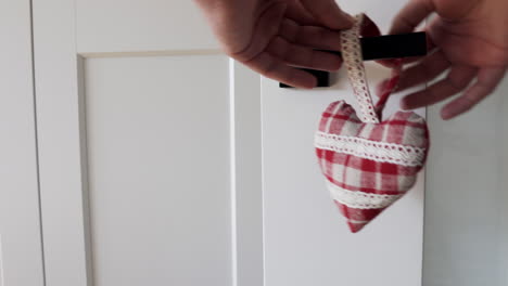 person hanging pendant heart hanger on the black door handle