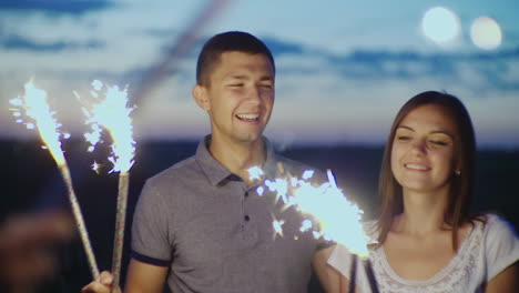 jóvenes divirtiéndose en una fiesta jugando con fuegos artificiales y luces de bengala en cámara lenta video de 10 bits