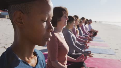 multi-ethnic group of women doing yoga position on the beach and blue sky background