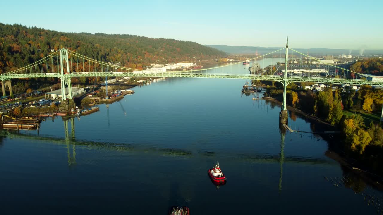 미국, 포틀랜드, 세인트 존스 브리지, 2024-11-07 - 새벽에 강철 다리의 드론 뷰. 놀라운 반사와 함께 물에 두 개의 견인 보트.