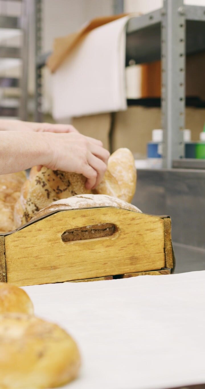 Baker Arranging Freshly Baked Bread in a Wooden Crate