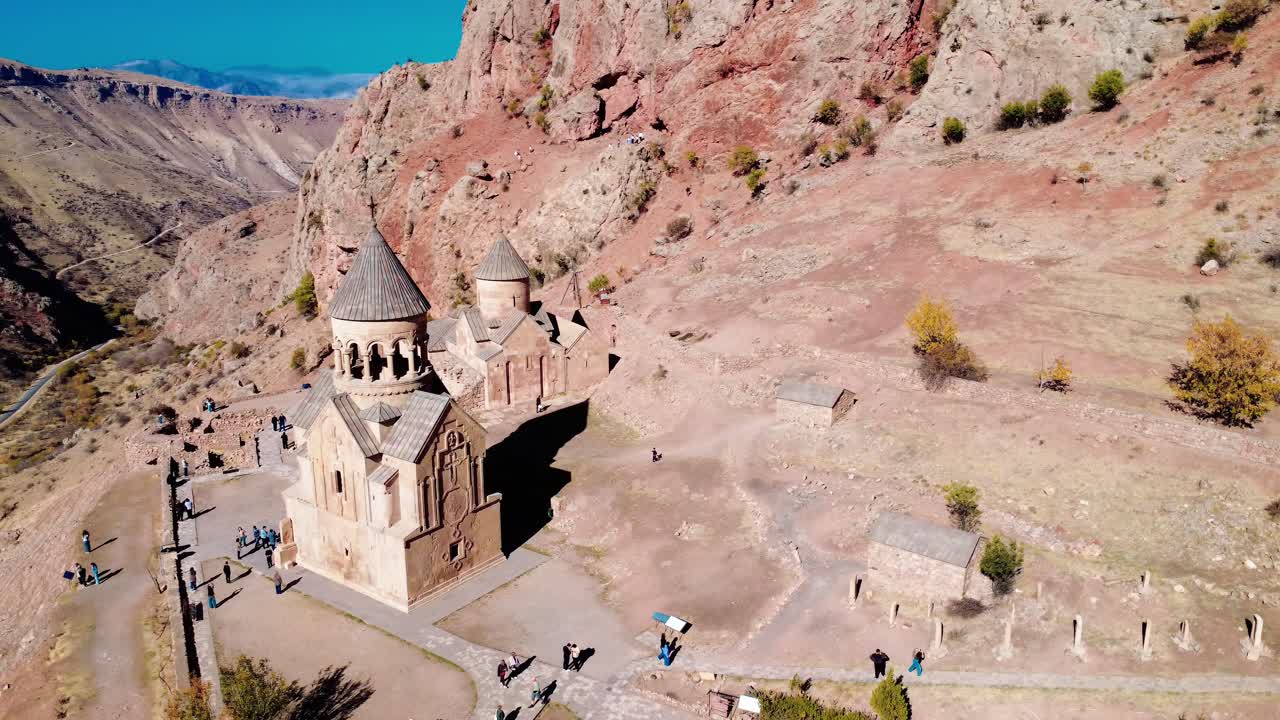 Monastero di Noravank di Areni, Armenia, con i canyon di roccia rossa e turisti sotto cieli blu tersi