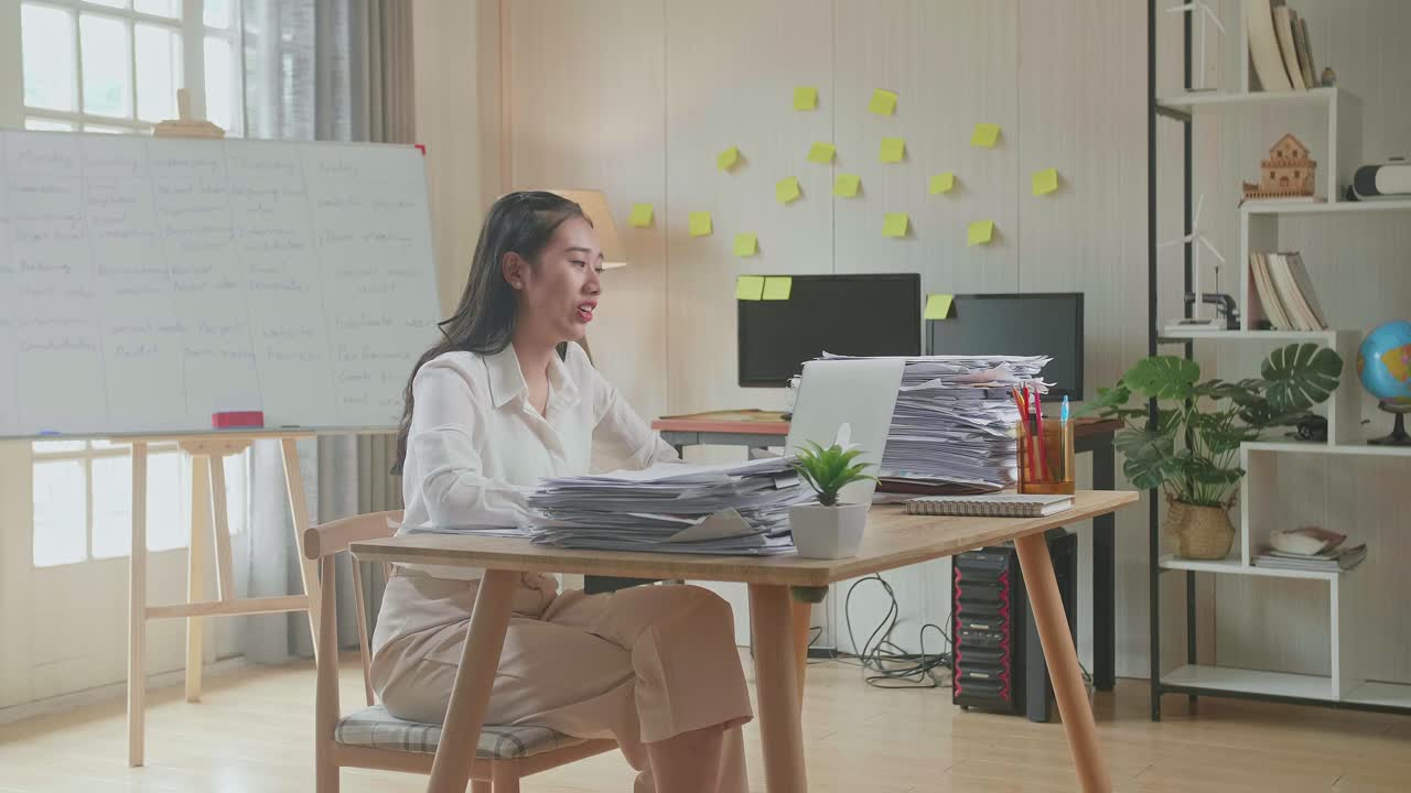 사무실 에서 문서 를 처리 하는 동안 노트북 으로 비디오 통화를 하는 아시아인 여자