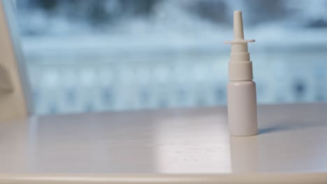 botella de spray nasal empujada y cayendo sobre la mesa de superficie blanca, movimiento lento